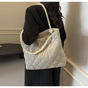 Close-up of beige quilted tote bag with chunky white cotton rope handles and fabric texture