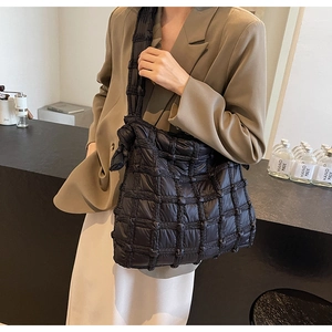Vue détaillée du sac à bandoulière matelassé noir avec texture tissée et nœud fixe