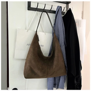 Detail of a large brown suede Hobo bag hanging on a hook in a natural lifestyle setting