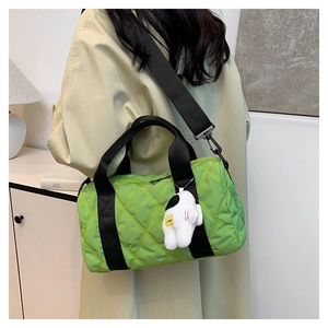 Detail view of bright green quilted nylon bag with black straps and astronaut pendant