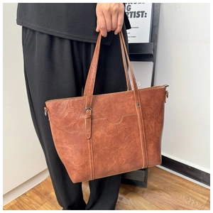 Gros plan du sac cabas en cuir marron vintage montrant la texture et la poche avant