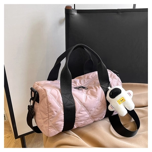 Detail of pink quilted nylon cylindrical handbag with astronaut plush charm and black strap