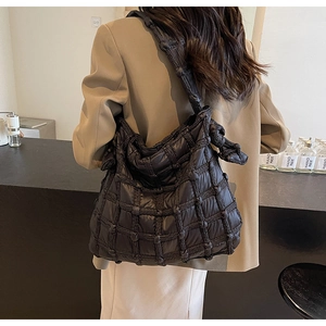 Détail du sac hobo noir matelassé avec bandoulière nouée dans un décor intérieur chic