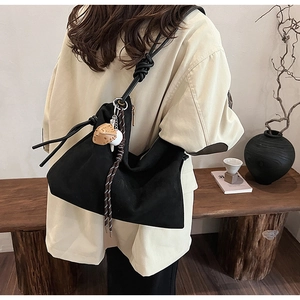 Détail du sac hobo noir avec bandoulière à nœuds épais et pendentif en peluche