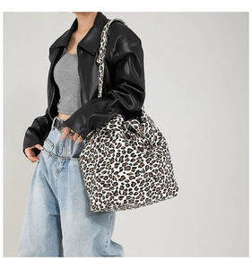 Close-up of leopard print canvas tote bag with wide shoulder strap on a model