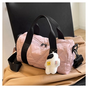 Detailed close-up of pink quilted nylon barrel bag with astronaut plush charm