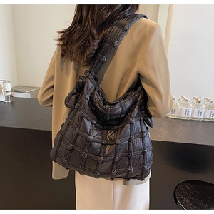 Gros plan du sac à bandoulière matelassé noir avec détail de nœud tissé et texture douce