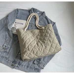 Chic beige quilted tote bag with white woven rope handles on casual denim background