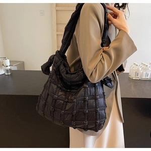 Détail de vue latérale du sac à bandoulière matelassé noir avec nœud sur la sangle