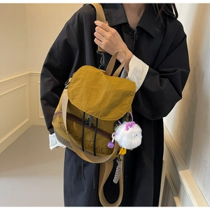 Détail d'un sac en nylon jaune gingembre et marron avec breloque peluche et style automne