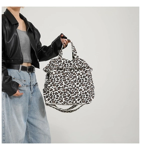 Detail of leopard print canvas tote bag featuring double handles and crossbody strap