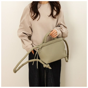 Detail view of sage green quilted puffer handbag with soft cotton padding and knotted straps