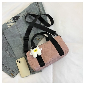 Detail of pink quilted nylon crossbody bag with astronaut plush charm and wide strap