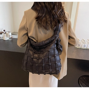 Détail d'un sac à bandoulière matelassé noir avec texture douce et large bandoulière