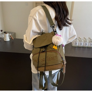 Détail d'un sac à dos en nylon vert olive avec broderie et pendentif en peluche blanche
