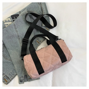 Detail view of pink quilted nylon barrel bag with black handles and adjustable strap