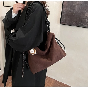 Détail d'un grand sac cabas en daim marron avec pendentif baseball et bandoulière noire