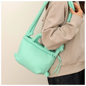 Detail of mint green quilted nylon shoulder bag with stylish knotted strap design