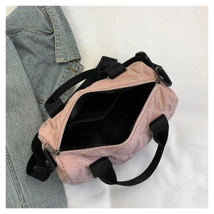 Detail view of pink quilted nylon barrel bag with black webbing straps and interior lining