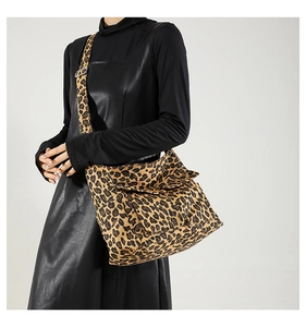 Detail of trendy leopard print shoulder bag with wide adjustable strap worn by a model