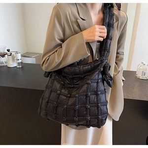 Détail du sac bandoulière en nylon matelassé noir avec bandoulière nouée et texture carrée