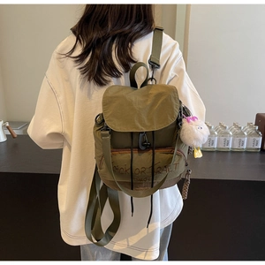 Gros plan sur le sac à dos en nylon vert olive avec cordon de serrage et charm canard en peluche