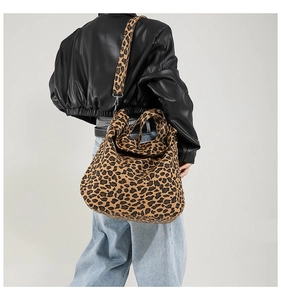 Detailed view of leopard print canvas tote bag with wide shoulder strap worn by model