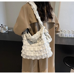 Détail du sac hobo blanc tressé et matelassé porté avec un trench-coat kaki élégant