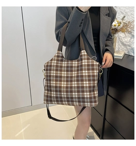 Close-up of brown checkered tote bag featuring durable webbing handles and metal D-rings