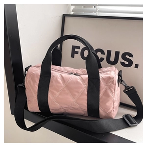 Pink quilted nylon barrel bag with black handles and adjustable crossbody strap