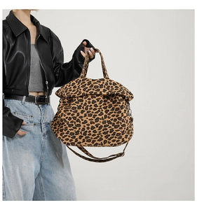 Detail of a large leopard print canvas tote bag with top handles and crossbody strap