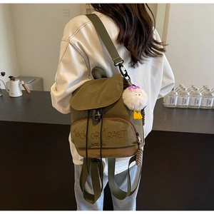 Détail du sac à dos en toile olive avec broderie Trick OR Treat et pendentif en peluche
