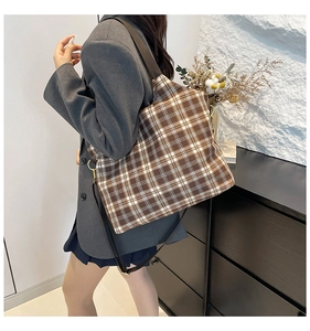 Detail of checkered tote bag showing wide shoulder strap and brown crossbody strap