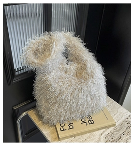 Gros plan sur la texture en fausse fourrure douce de ce sac à main blanc crème