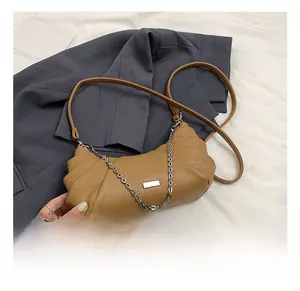 Detail of caramel half-moon dumpling bag with silver chain and lychee leather texture