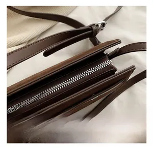 Detail shot of the silver metal zipper closure on a dark brown vintage suede crossbody bag