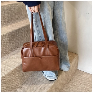 Detail of a brown PU leather shoulder bag featuring a front pocket and zipper closure