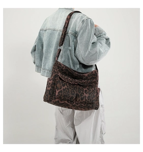 Detail of leopard print canvas crossbody bag featuring adjustable wide strap and outer pocket