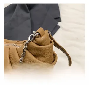 Detailed macro view of caramel lychee grain leather handbag with silver chain hardware