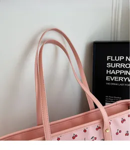Gros plan d'un sac cabas rose avec imprimé cerise et rivets métalliques dorés sur l'anse