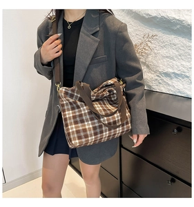 Brown checkered canvas tote bag with adjustable shoulder strap shown on a model