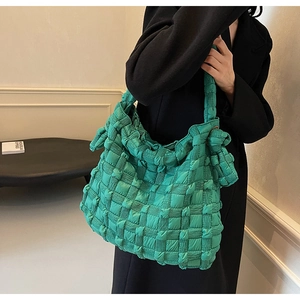 Détail du sac fourre-tout tissé vert vif avec texture matelassée sur un manteau noir