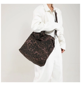 Detail of leopard print canvas tote bag featuring wide shoulder straps and textile texture