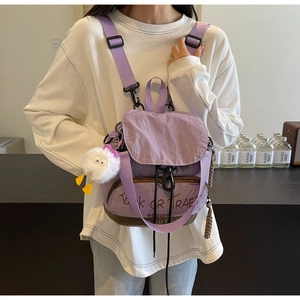Détail d'un sac à dos violet en nylon avec rabat à cordon et breloque poulet en peluche