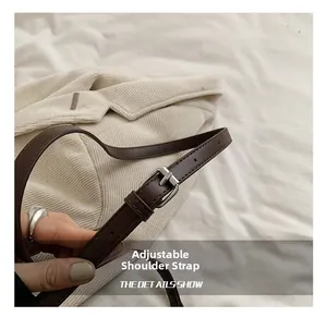 Detailed macro view of adjustable brown leather shoulder strap with silver metal buckle