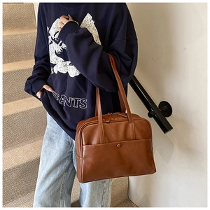 Close-up detail of the brown PU leather shoulder bag featuring a front pocket and fine stitching