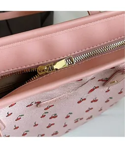 Gros plan sur le sac fourre-tout rose à imprimé cerise et fermeture éclair en métal doré