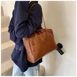 Brown vintage PU leather shoulder bag shown on model in a minimalist setting