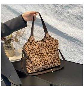 Detailed macro shot of stylish leopard print fabric tote bag with adjustable brown strap