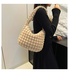 Detail of beige quilted shoulder bag with puffy textured squares and wide strap